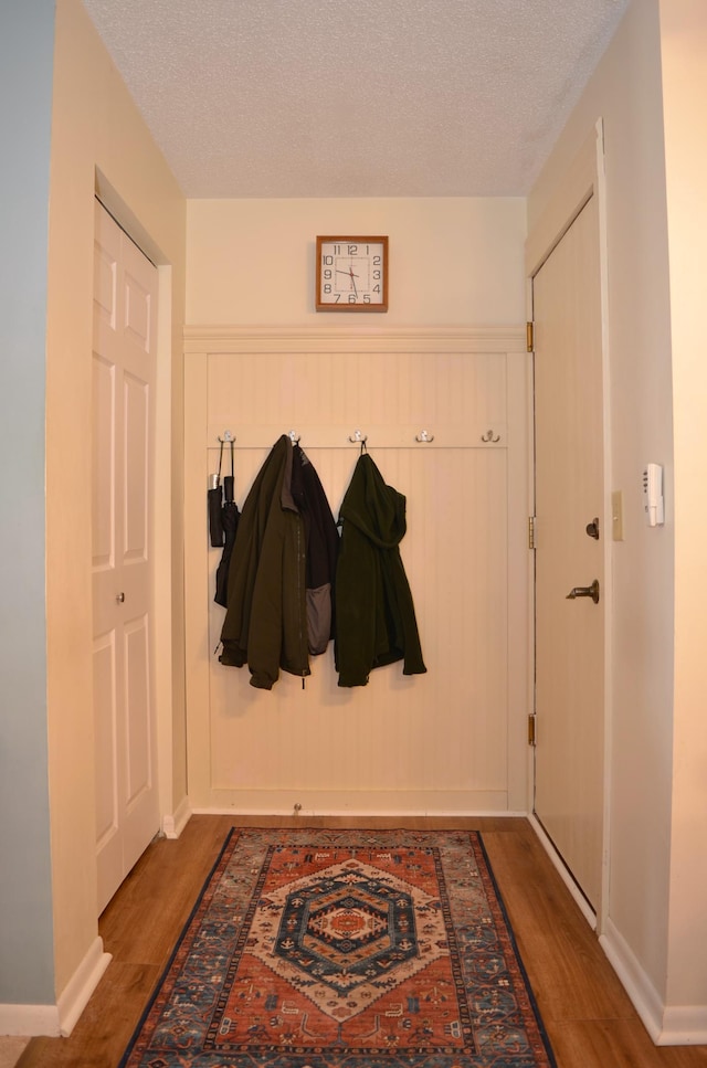 mudroom featuring a textured ceiling, baseboards, and wood finished floors