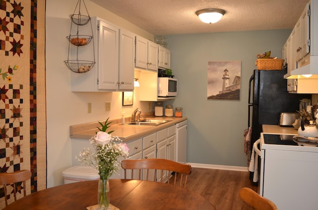 kitchen featuring white appliances, dark wood finished floors, white cabinets, light countertops, and a sink