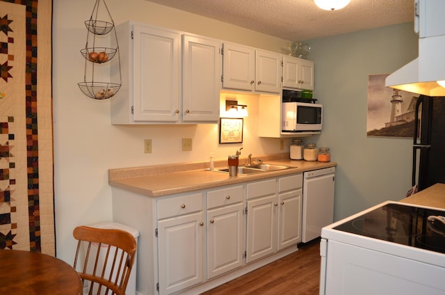 kitchen with white appliances, light countertops, a textured ceiling, white cabinetry, and a sink