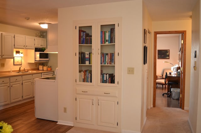 hallway with light wood finished floors, baseboards, and a sink