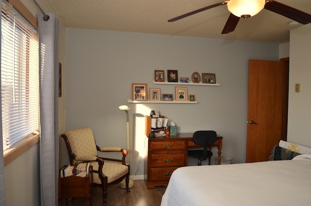 bedroom featuring a ceiling fan, a textured ceiling, baseboards, and wood finished floors