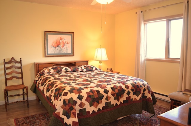 bedroom with baseboards, baseboard heating, and wood finished floors