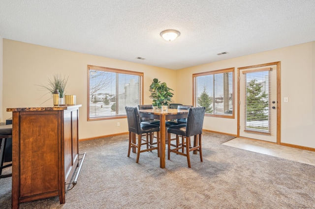 carpeted dining space with baseboards, a textured ceiling, and visible vents