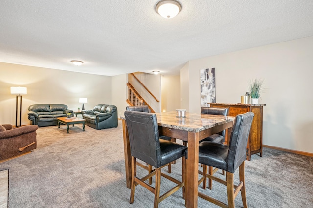 dining area featuring a textured ceiling, light colored carpet, baseboards, and stairway