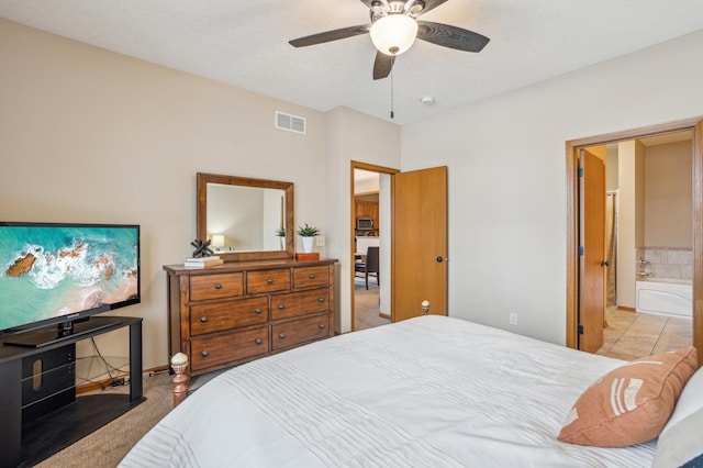 tiled bedroom featuring visible vents, carpet flooring, connected bathroom, and ceiling fan