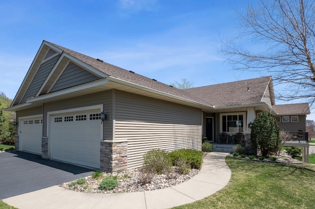 view of front of home featuring roof with shingles, an attached garage, a front yard, and aphalt driveway