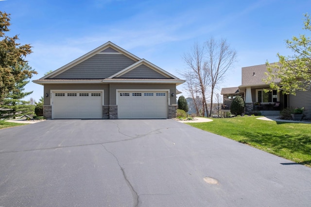 craftsman-style home with an attached garage, a front lawn, stone siding, and aphalt driveway