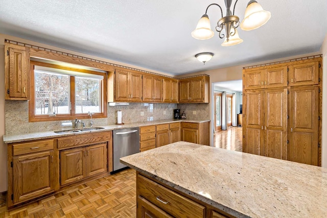 kitchen featuring a sink, tasteful backsplash, a textured ceiling, brown cabinetry, and dishwasher