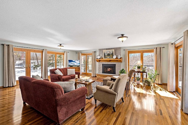 living area with a healthy amount of sunlight, a fireplace, french doors, and wood-type flooring