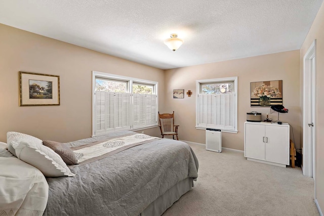 bedroom with light colored carpet, baseboards, and a textured ceiling