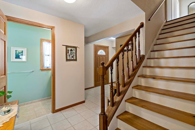 stairs with tile patterned floors, baseboards, and a textured ceiling