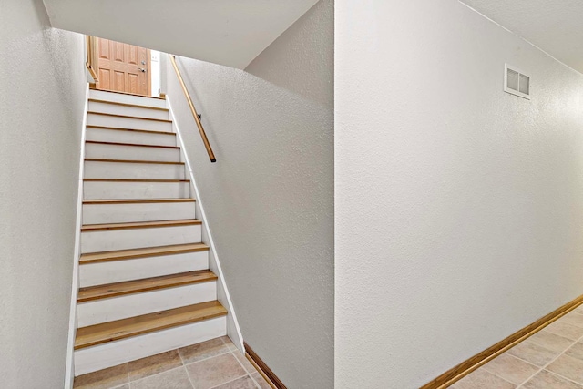 stairs featuring visible vents, baseboards, and a textured wall