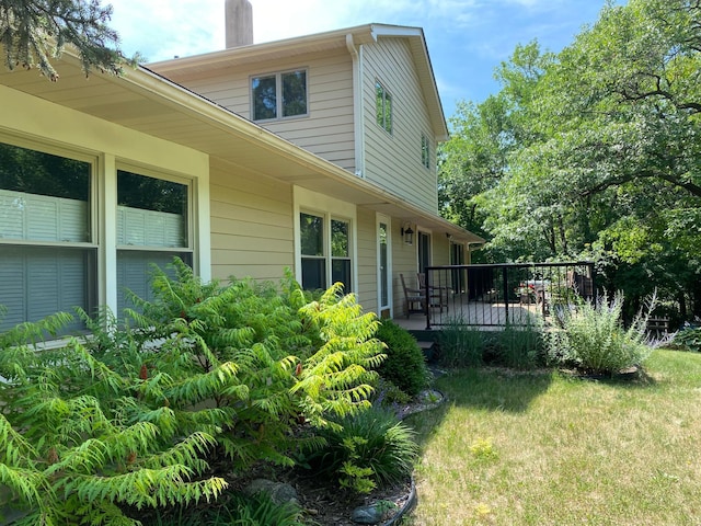 view of home's exterior with a deck, a chimney, and a yard