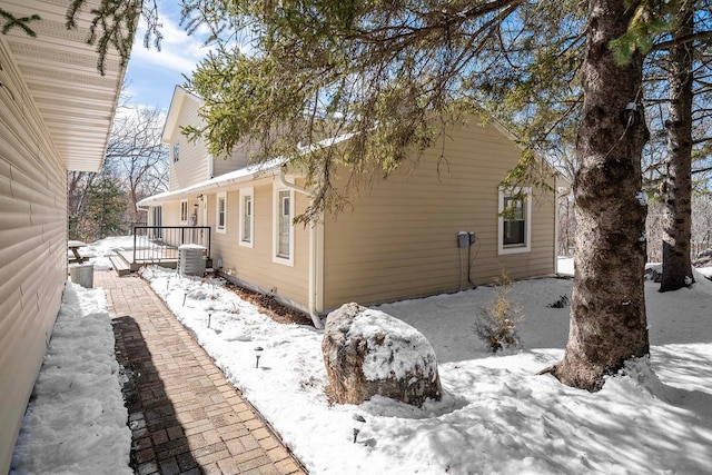 view of snowy exterior featuring a porch and central air condition unit