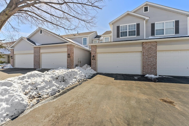 view of front of house with a garage, brick siding, and driveway