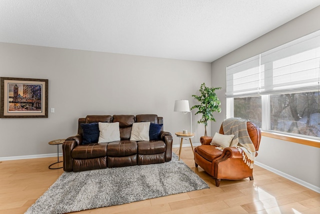 living area featuring light wood-style floors, baseboards, and a textured ceiling