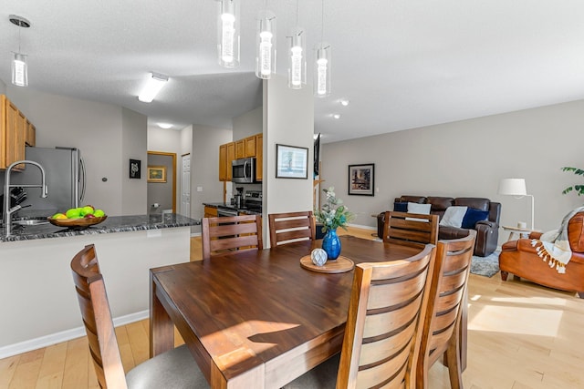 dining area featuring a textured ceiling, light wood-type flooring, and baseboards