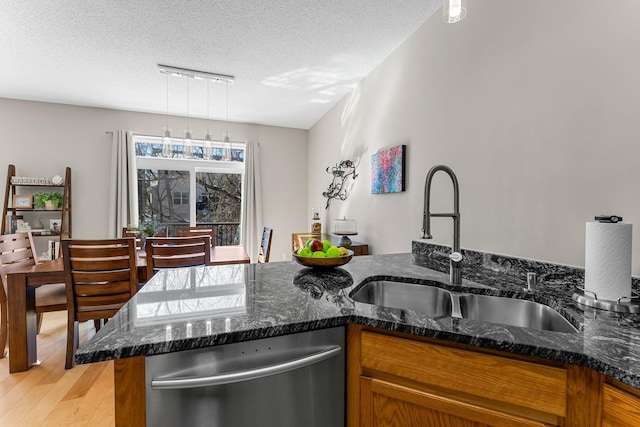 kitchen with a sink, light wood-type flooring, dishwasher, and brown cabinetry