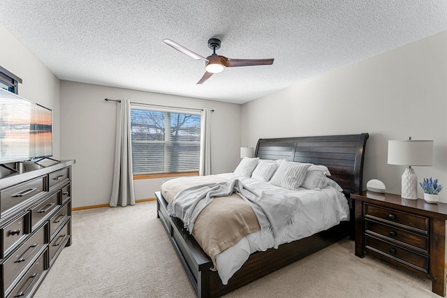 bedroom featuring light colored carpet, a textured ceiling, baseboards, and a ceiling fan