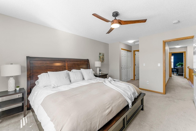 bedroom with baseboards, light carpet, a closet, a textured ceiling, and a ceiling fan