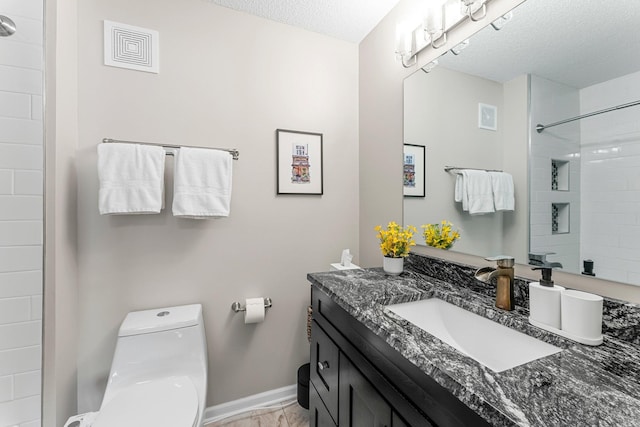 full bathroom featuring toilet, a textured ceiling, vanity, and baseboards