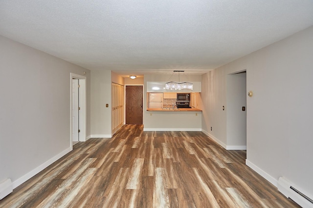 unfurnished living room featuring a textured ceiling, a notable chandelier, dark wood-style flooring, baseboards, and baseboard heating