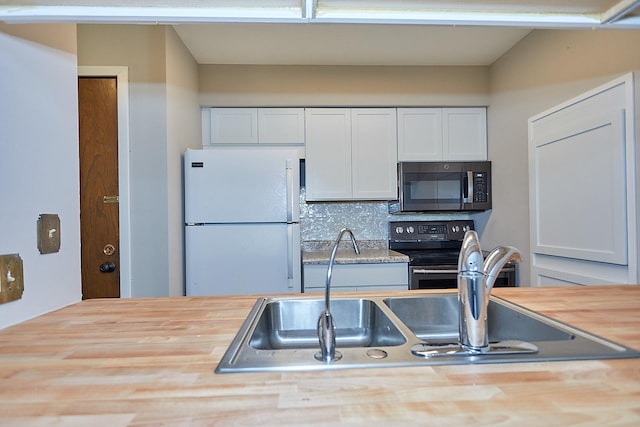 kitchen with range with electric stovetop, a sink, white cabinets, freestanding refrigerator, and stainless steel microwave