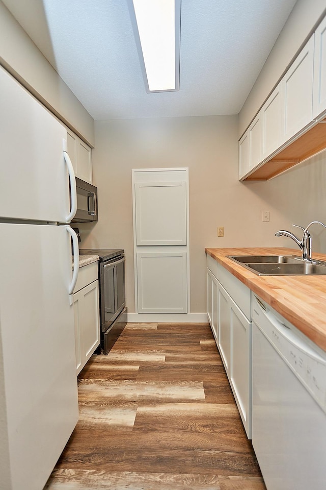 kitchen with white appliances, a sink, white cabinetry, light wood-style floors, and wooden counters