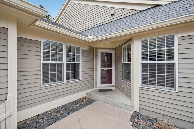 view of exterior entry with a shingled roof