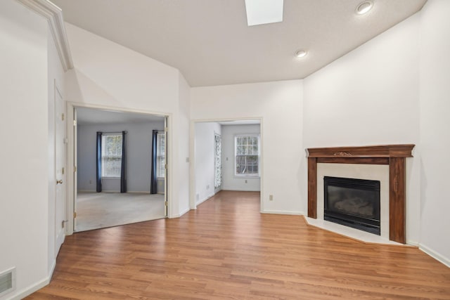 unfurnished living room with a fireplace with flush hearth, baseboards, visible vents, and light wood finished floors