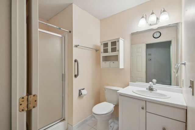 bathroom featuring tile patterned flooring, toilet, vanity, baseboards, and a stall shower