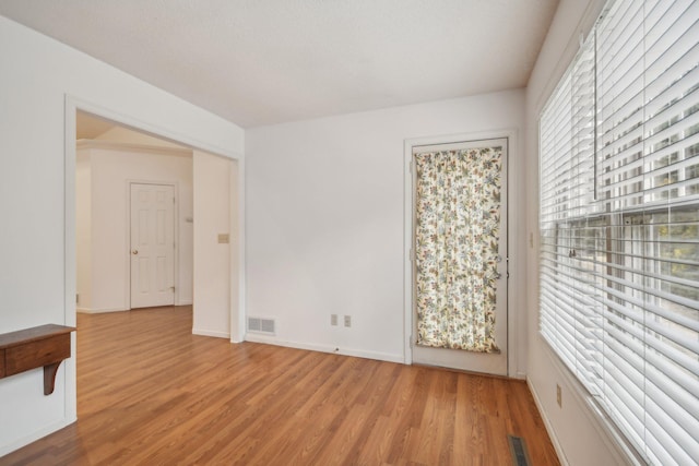 empty room with visible vents, baseboards, and wood finished floors