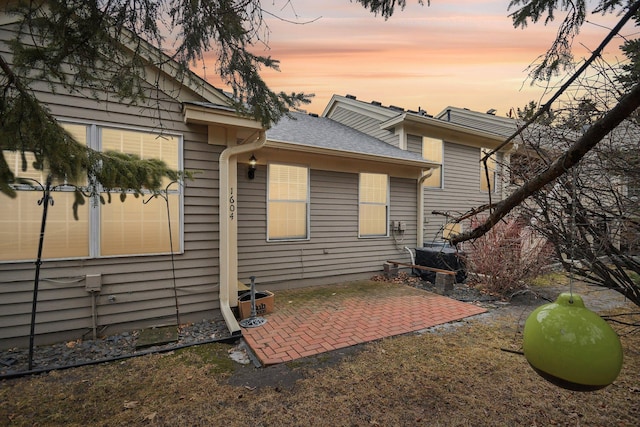 back of property featuring a patio area and a shingled roof