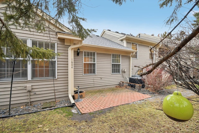 back of property featuring roof with shingles and a patio