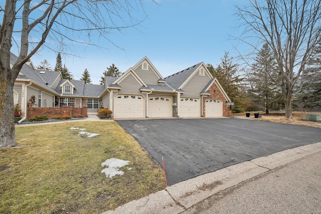 view of front of house with an attached garage, brick siding, a front yard, and aphalt driveway