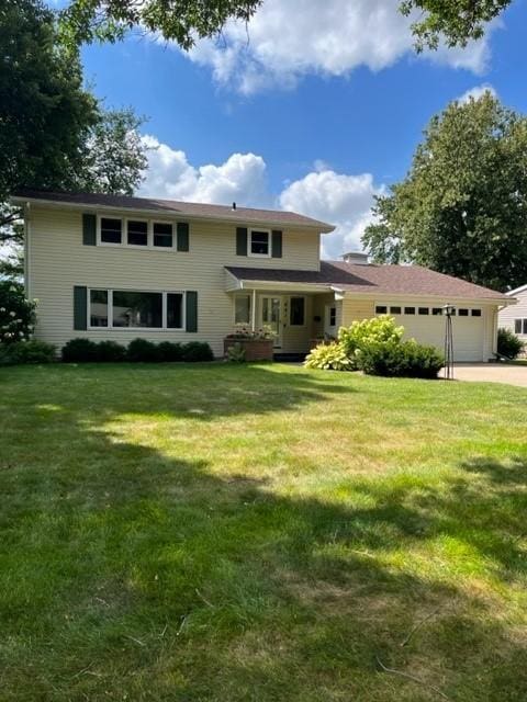 traditional-style home featuring a garage and a front lawn