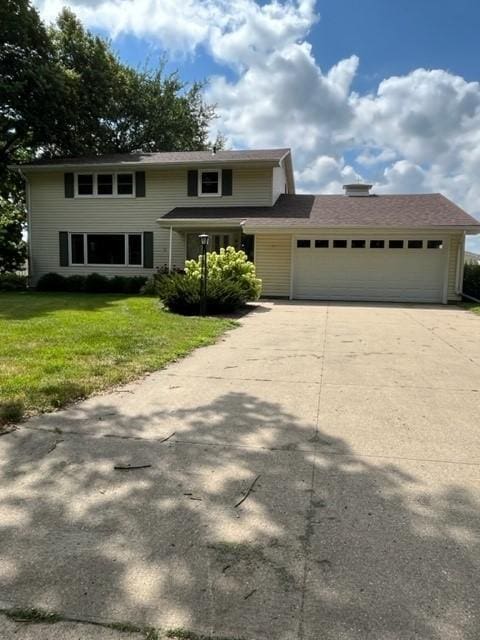 traditional-style house with a garage, driveway, and a front yard