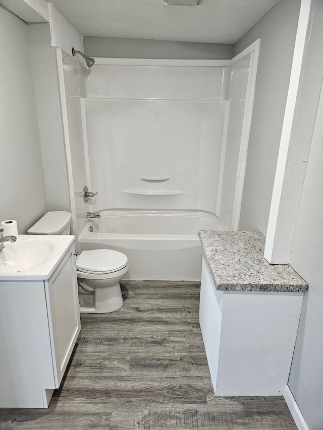 full bath featuring toilet, tub / shower combination, wood finished floors, and vanity