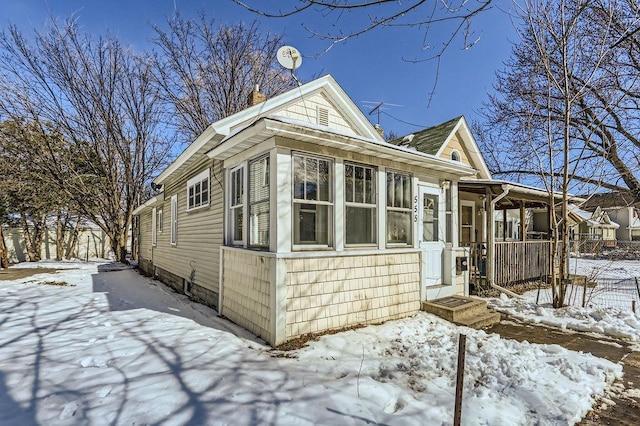 view of snow covered exterior featuring fence and a sunroom