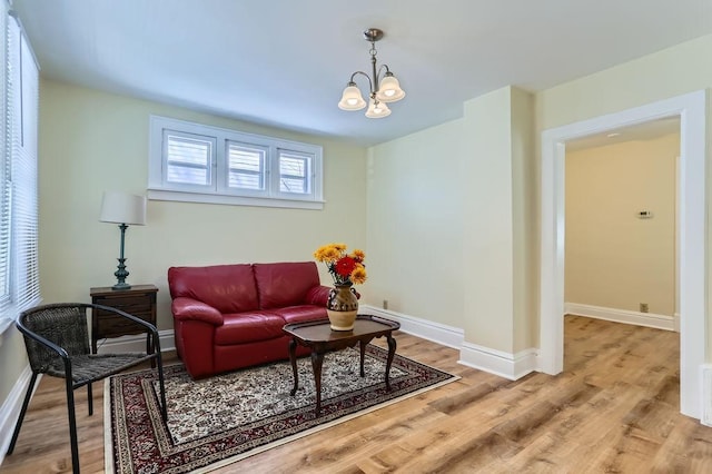 living area featuring a notable chandelier, light wood finished floors, and baseboards