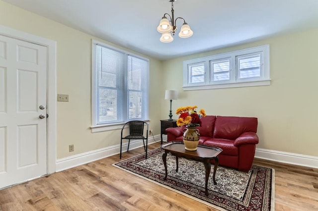 living room featuring a notable chandelier, baseboards, and wood finished floors