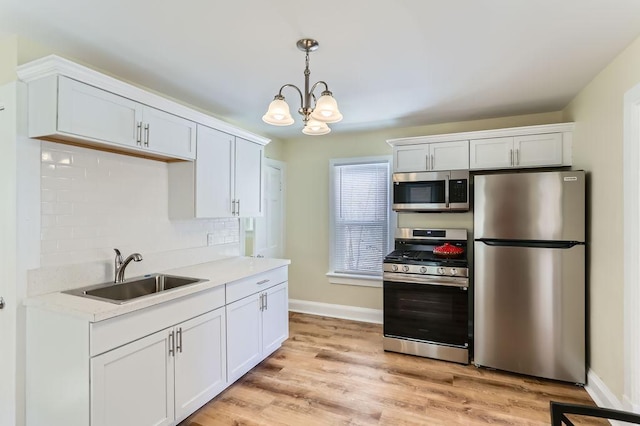 kitchen featuring stainless steel appliances, a sink, hanging light fixtures, light countertops, and decorative backsplash