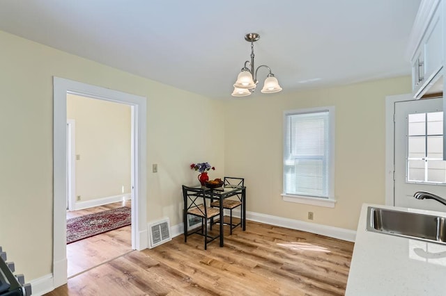 dining area featuring a notable chandelier, visible vents, baseboards, and light wood-type flooring