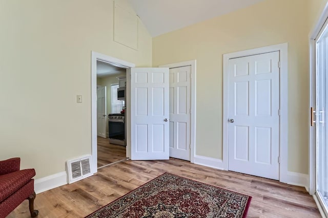 bedroom with baseboards, visible vents, high vaulted ceiling, and light wood-type flooring
