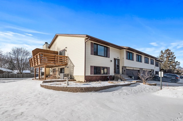 view of front of property with a garage, a chimney, a wooden deck, and central air condition unit