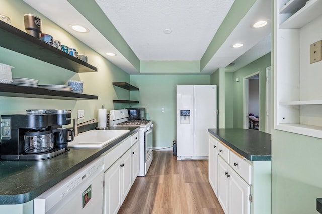 kitchen featuring open shelves, light wood-style floors, white cabinetry, a sink, and white appliances