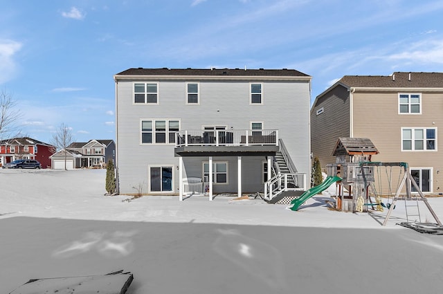 rear view of property featuring a playground, a wooden deck, and stairs