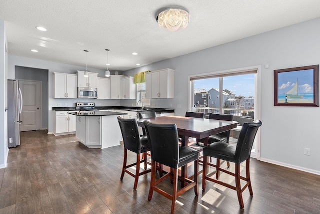 dining area with a textured ceiling, recessed lighting, dark wood finished floors, and baseboards