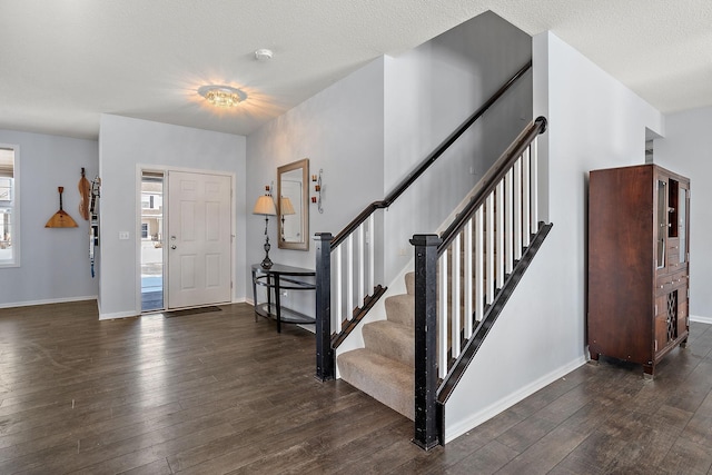 foyer with a textured ceiling, wood-type flooring, stairs, and baseboards