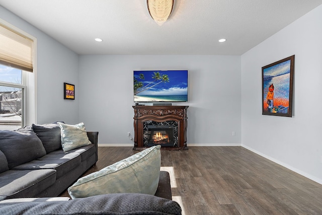 living room featuring hardwood / wood-style flooring, recessed lighting, baseboards, and a glass covered fireplace